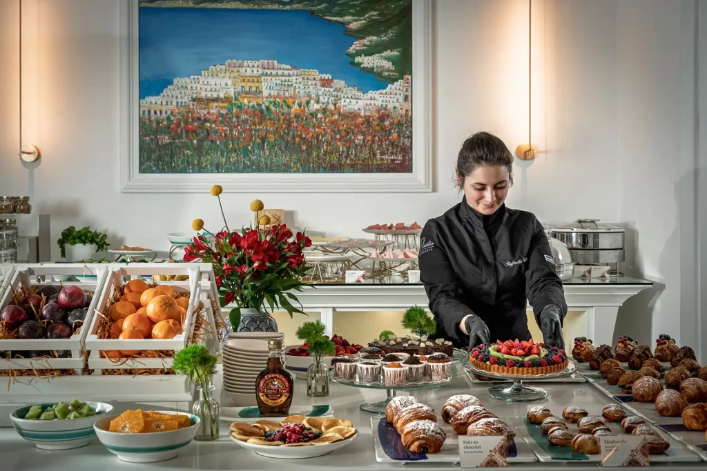 Chef che prepara un buffet di dolci e frutta in una raffinata sala da pranzo.