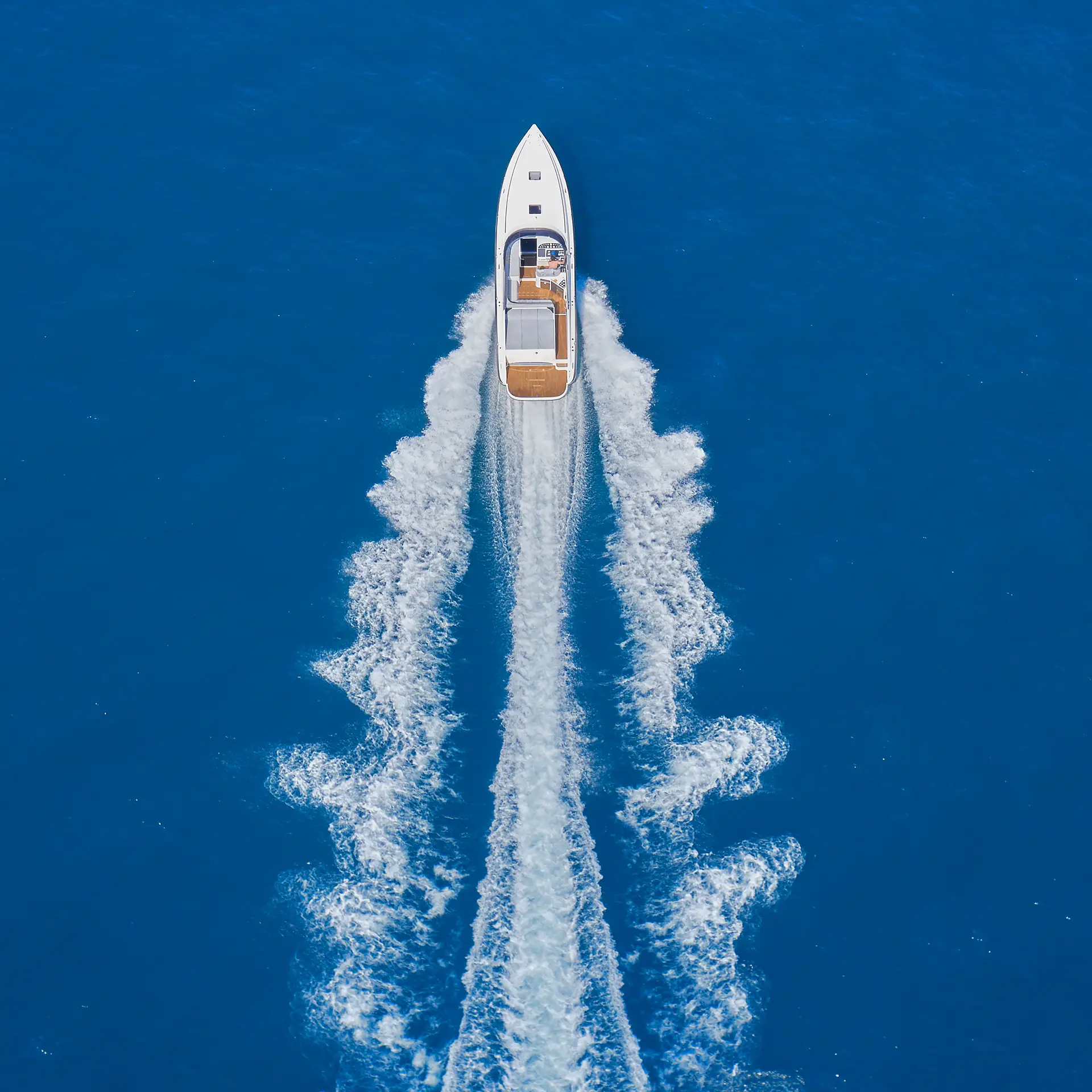 Aerial view of a boat creating a wake on blue water.
