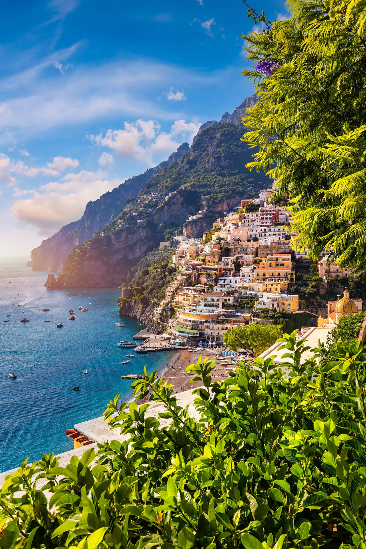 Scenic view of colorful buildings on a hillside overlooking a clear blue sea with boats.