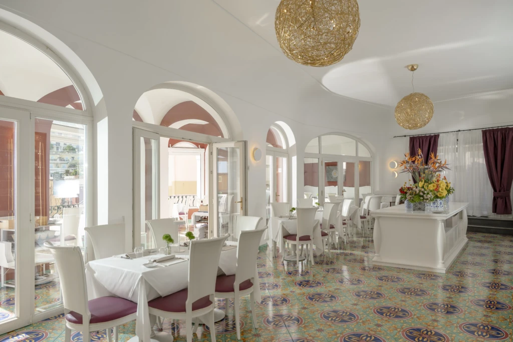 Un elegante ristorante con decorazioni floreali, pavimenti colorati e ampie finestre ad arco.